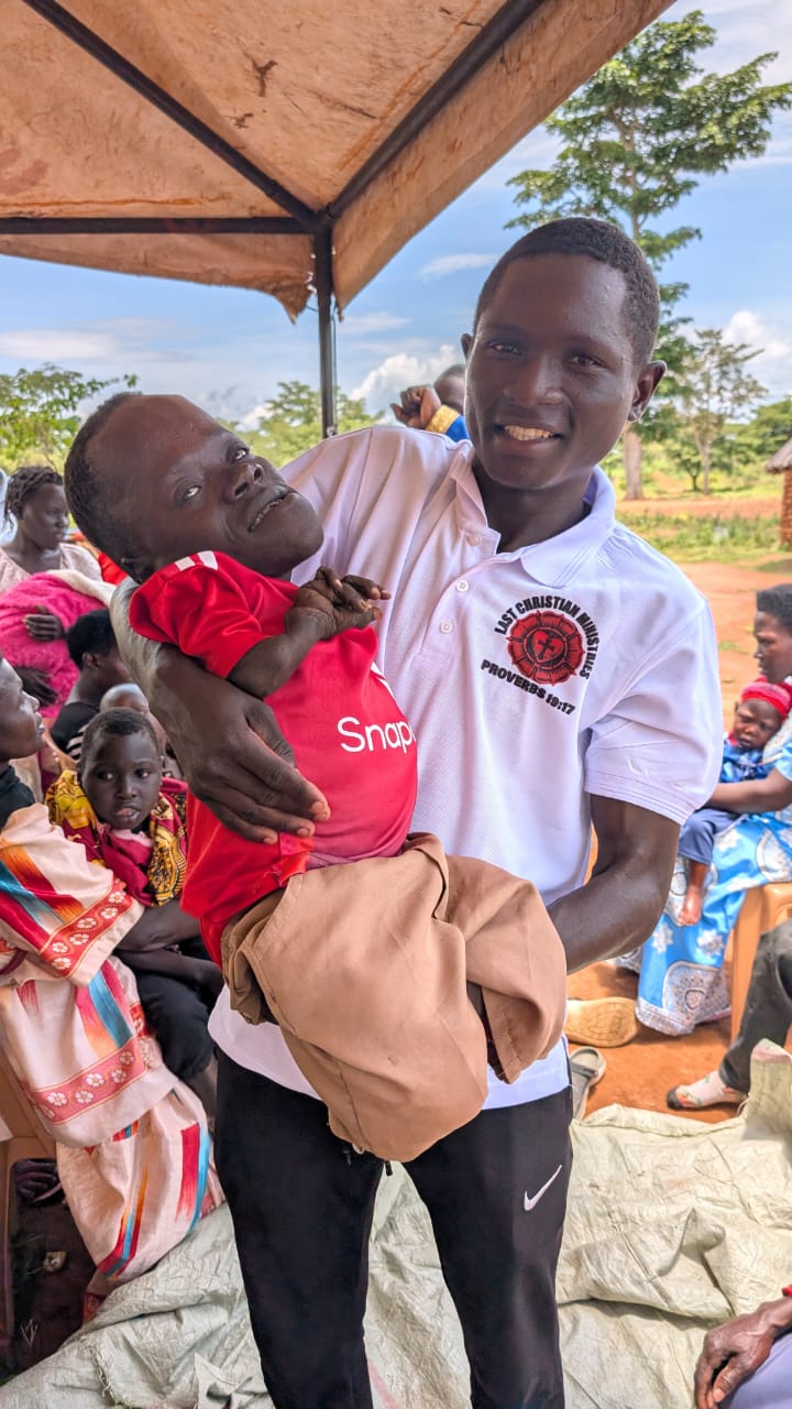 Kutesa Henry holding a disabled child during the Easter distribution.