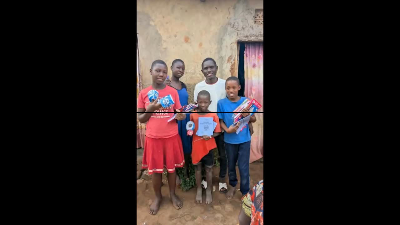Children in Uganda standing with Kutesa Henry and holding school supplies from the June 2026 distribution.